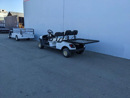 White golf cart modified with a large flatbed custom fabricated deck, shown with CUSH-SHUTTLE-DECK48X48-SP CUSHMAN SHUTTLE CARGO DECK WITH STAKE POCKETS, designed for cargo and utility use.