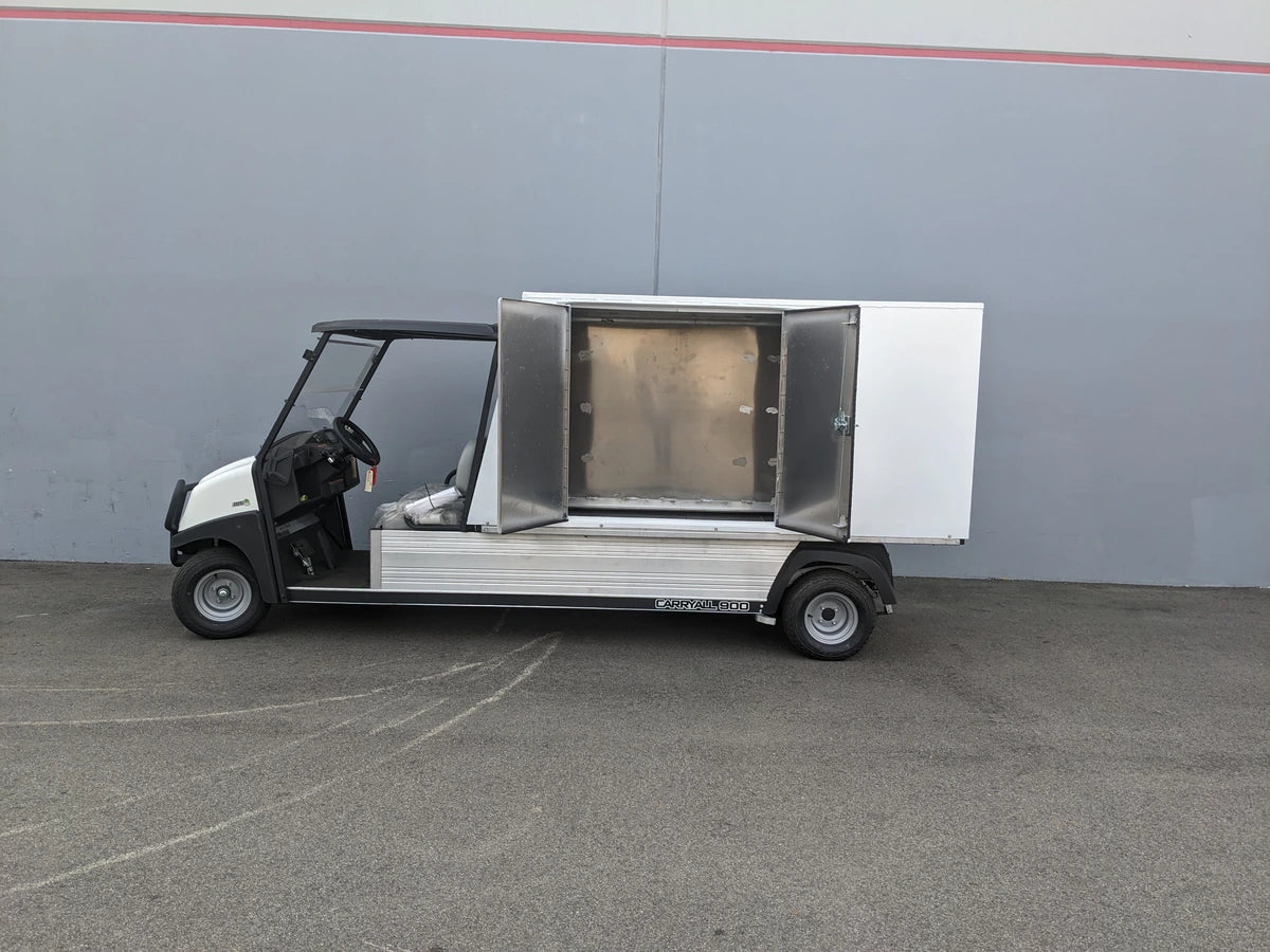 Golf utility vehicle equipped with the CC-CARRYALL900-LAUNDRY BOX FLATBED SPECIFIC PURPOSE BOX FOR CARRYALL 900 WITH LOCKING DOORS, SHELVES, AND HANGING ROD, featuring an open storage compartment.