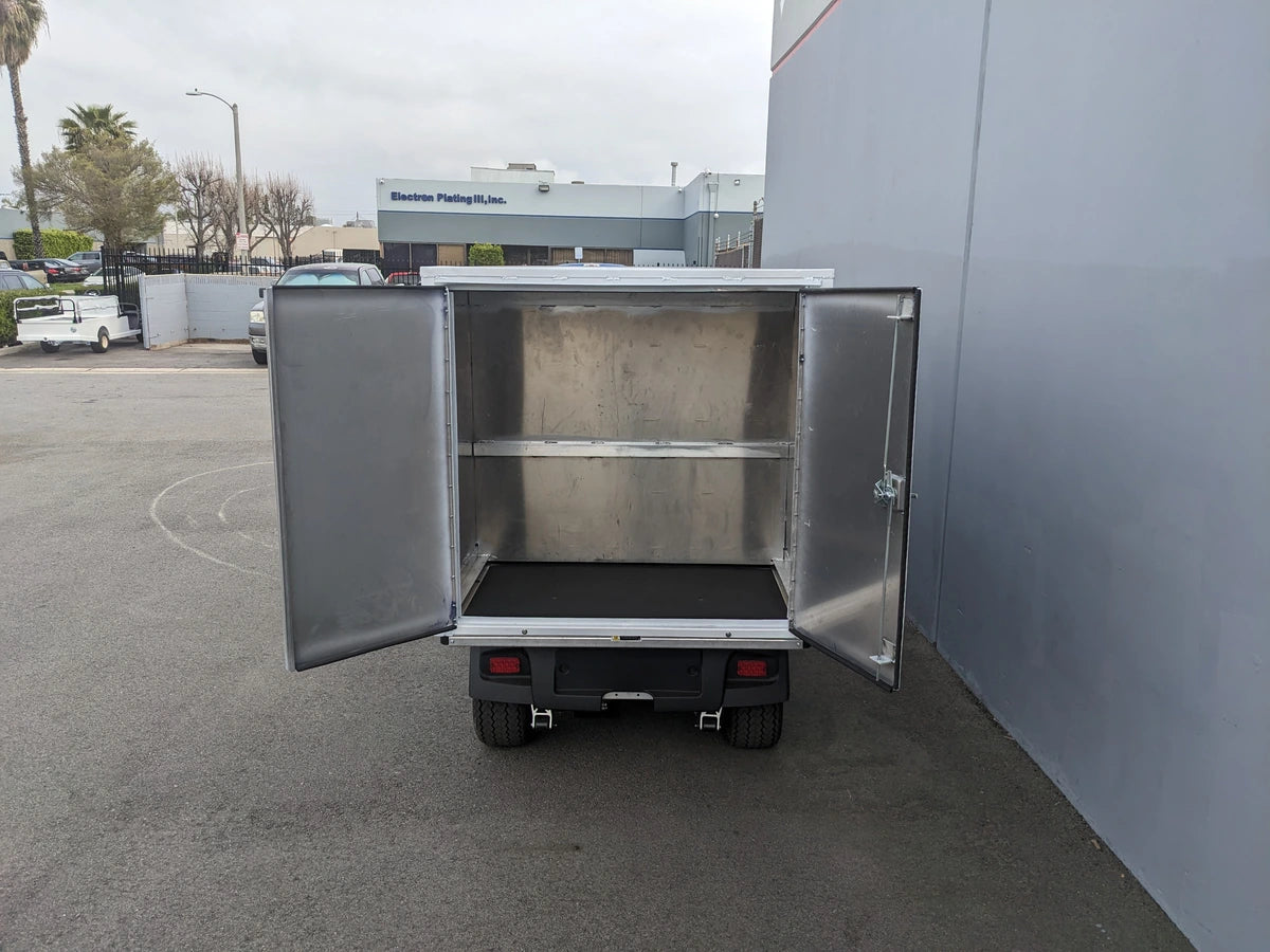 Open rear view of CC-CARRYALL900-LAUNDRY BOX FLATBED SPECIFIC PURPOSE BOX FOR CARRYALL 900 WITH LOCKING DOORS, SHELVES, AND HANGING ROD mounted on a utility vehicle with interior shelves and hanging rod visible.