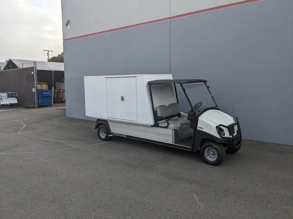 CC-CARRYALL900-LAUNDRY BOX FLATBED SPECIFIC PURPOSE BOX FOR CARRYALL 900 WITH LOCKING DOORS, SHELVES, AND HANGING ROD mounted on a utility golf cart in an industrial setting.