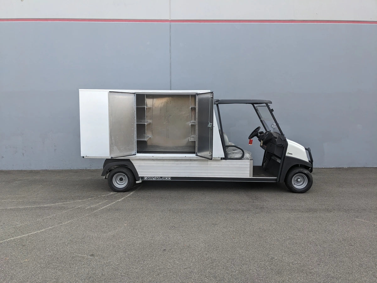 Utility vehicle equipped with the CC-CARRYALL900-LAUNDRY BOX FLATBED SPECIFIC PURPOSE BOX FOR CARRYALL 900 WITH LOCKING DOORS, SHELVES, AND HANGING ROD, featuring open storage compartment with shelves and hanging rod for organized cargo and equipment.