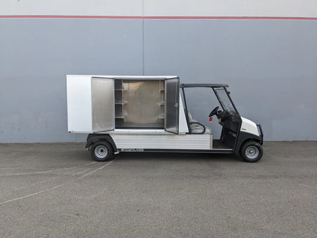 Utility vehicle equipped with the CC-CARRYALL900-LAUNDRY BOX FLATBED SPECIFIC PURPOSE BOX FOR CARRYALL 900 WITH LOCKING DOORS, SHELVES, AND HANGING ROD, featuring open storage compartment with shelves and hanging rod for organized cargo and equipment.