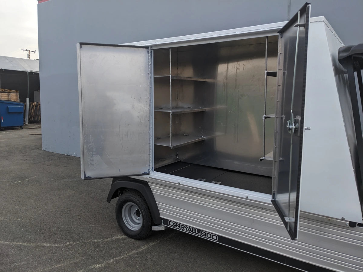 Open metal utility box attached to a flatbed vehicle showing interior shelves and hanging rod, designed for organized storage, identified as CC-CARRYALL900-LAUNDRY BOX FLATBED SPECIFIC PURPOSE BOX FOR CARRYALL 900 WITH LOCKING DOORS, SHELVES, AND HANGING ROD.
