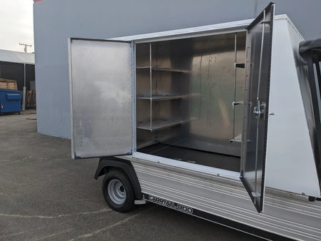 Open metal utility box attached to a flatbed vehicle showing interior shelves and hanging rod, designed for organized storage, identified as CC-CARRYALL900-LAUNDRY BOX FLATBED SPECIFIC PURPOSE BOX FOR CARRYALL 900 WITH LOCKING DOORS, SHELVES, AND HANGING ROD.