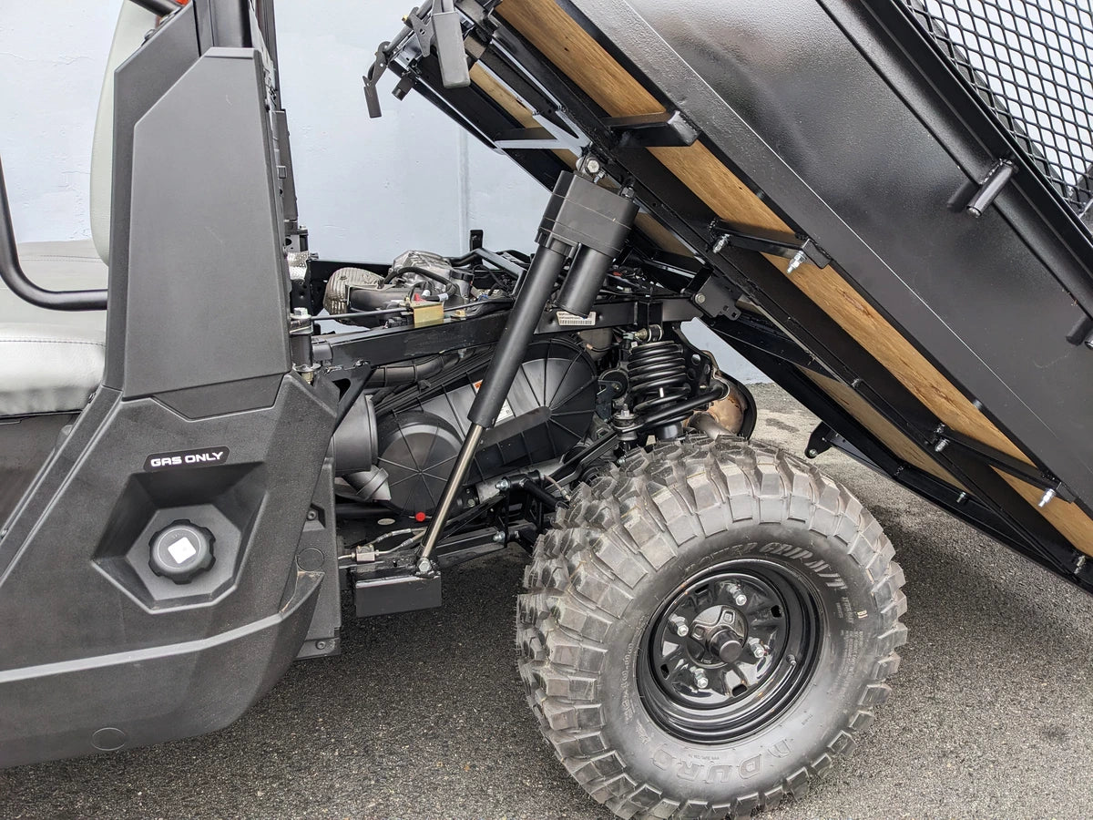 Close-up of a custom golf cart bed with FB-POL-PROXD-54X76X11-DUMP TILT BED ACTUATOR WITH KEY FOB REMOTE installing the tilt mechanism on a rugged off-road tire vehicle.