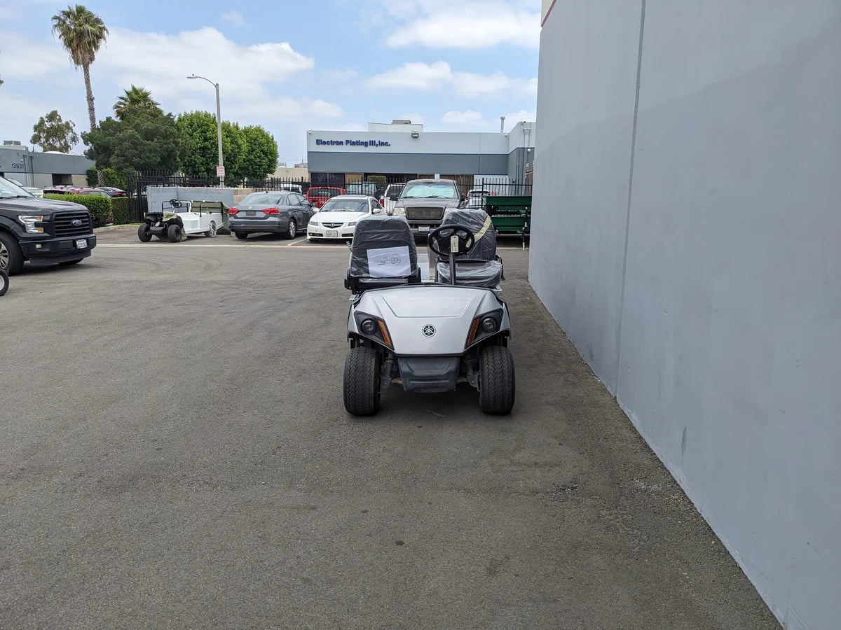 White and black YAM-AMB-2SEAT-REAREMT-96X23 AMBULANCE CART with two seats parked outside near a building, custom fabrication for golf carts visible in the design.