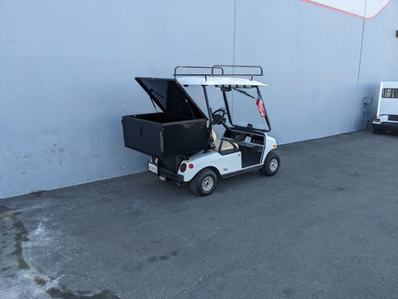 White golf cart equipped with a black CC-VILL-CARGO31 LOCKING CARGO BOX FOR CLUB CAR VILLAGER mounted on the back, custom fabricated for secure utility cargo transport.