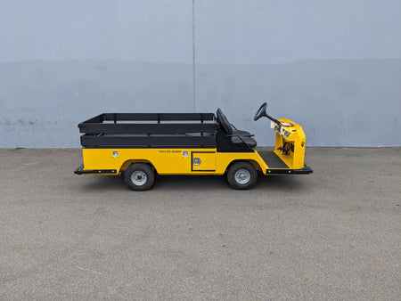BIGFOOT-DOOR-COMPARTMENT Pass Through Storage Cabinet for Taylor Dunn Bigfoot installed on a yellow utility cart hauler with flatbed cargo area and black railing.
