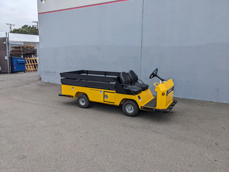 Yellow utility cart with two black seats and a flatbed storage area attached, featuring the BIGFOOT-DOOR-COMPARTMENT Pass Through Storage Cabinet for Taylor Dunn Bigfoot designed for cargo and utility use.