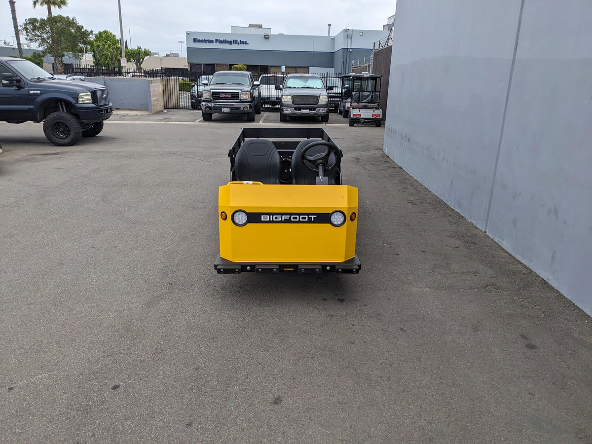 BIGFOOT-DOOR-COMPARTMENT Pass Through Storage Cabinet for Taylor Dunn Bigfoot installed on the back of a yellow utility cart in an outdoor industrial setting.