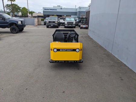 BIGFOOT-DOOR-COMPARTMENT Pass Through Storage Cabinet for Taylor Dunn Bigfoot installed on the back of a yellow utility cart in an outdoor industrial setting.