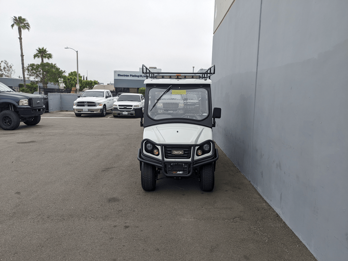 White utility golf cart equipped with CC-710-50X96-CHASSIS-TLRA-GUARD CLUB CAR 710 TOP LADDER RACK AND CAB GUARD parked next to a gray wall in an outdoor lot.