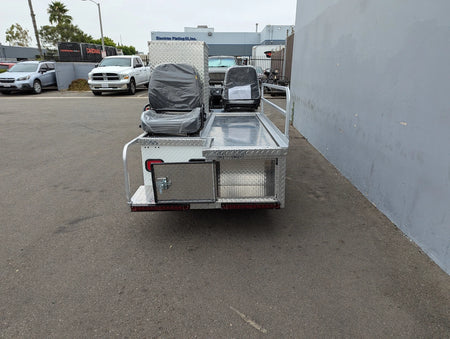 Rear view of a custom aluminum flatbed with two seats wrapped in protective covers, designed for CUSH-TITAN-3SEAT-84X23 Ambulance Conversion for Cushman Titan, showcasing utility box and safety rails, highlighting custom fabrication for golf carts.