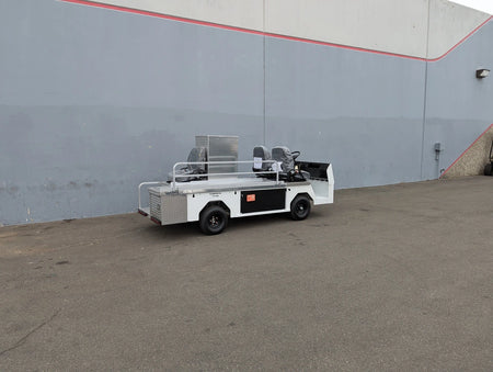 White utility vehicle with custom fabrication and storage compartments parked outdoors against a gray wall, featuring CUSH-TITAN-3SEAT-84X23 Ambulance Conversion for Cushman Titan design.