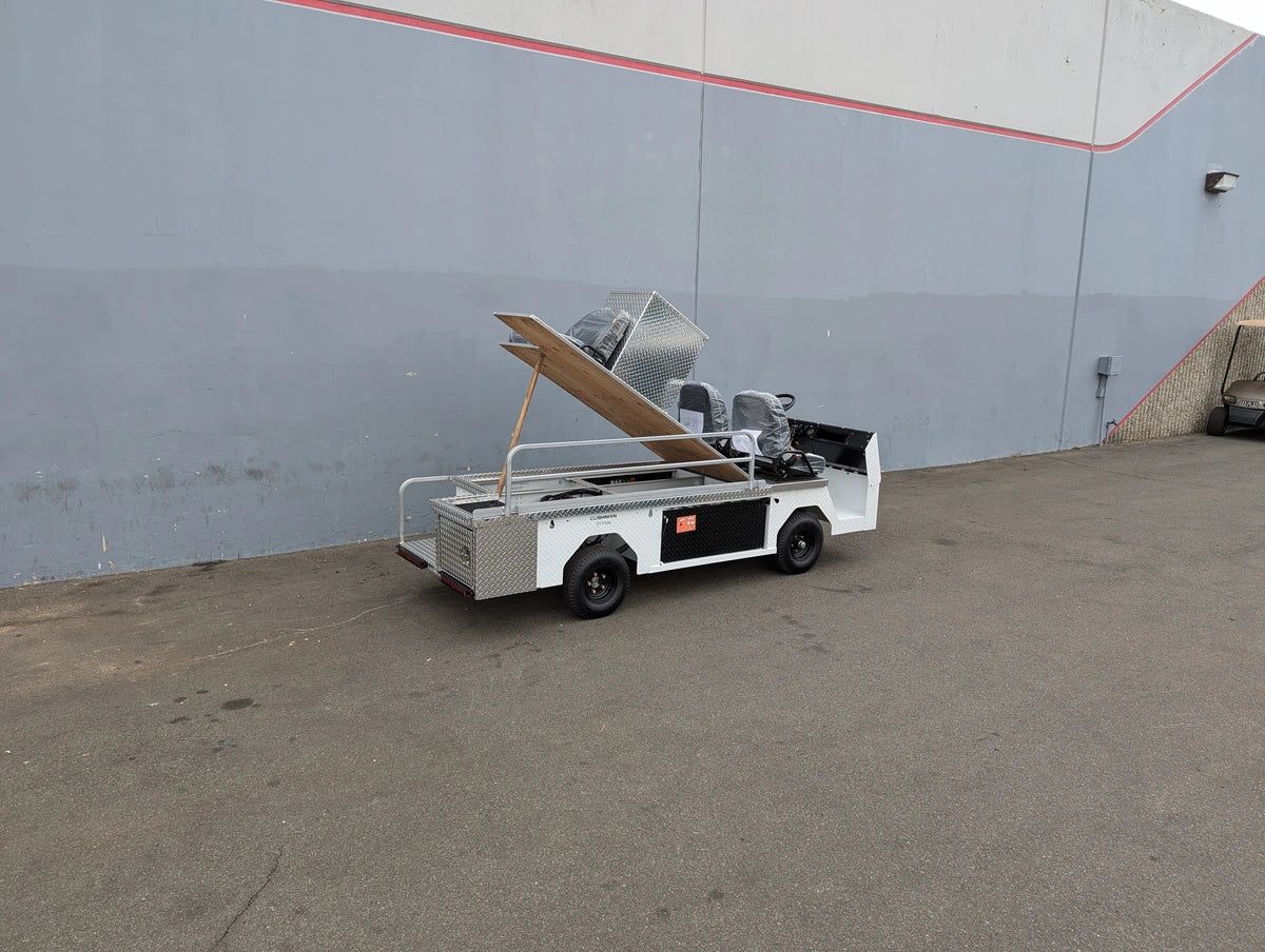 CUSH-TITAN-3SEAT-84X23 Ambulance Conversion for Cushman Titan with aluminum body and custom fabrication for golf carts parked outdoors near a gray building wall.