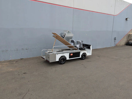 CUSH-TITAN-3SEAT-84X23 Ambulance Conversion for Cushman Titan with aluminum body and custom fabrication for golf carts parked outdoors near a gray building wall.