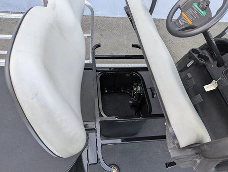 Open heavy-duty storage compartment between white cushioned seats in a golf cart showing custom fabrication for golf carts with the SEAT-POD-CC Heavy-Duty Club Car Seat Pod installed