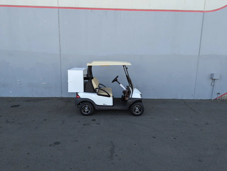 White golf cart equipped with a TB-36X18X28-FH BED MOUNT TOOLBOX WITH HINGED DOOR installed on the back, showcasing custom fabrication for golf carts utility and cargo storage.
