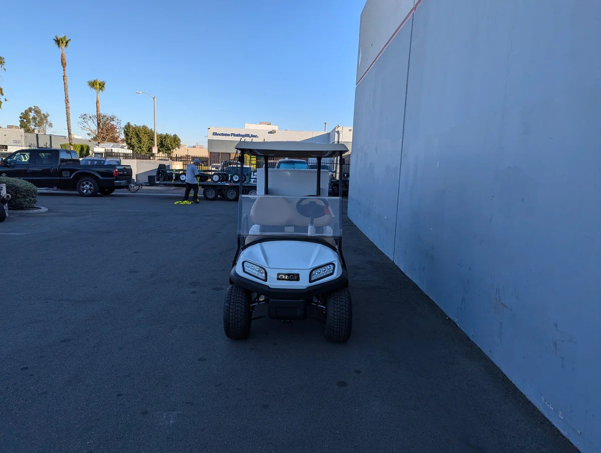 White golf cart parked outdoors next to a building, featuring a custom fabricated TB-36X18X28-FH BED MOUNT TOOLBOX WITH HINGED DOOR designed for golf cart accessory cargo and utility storage.