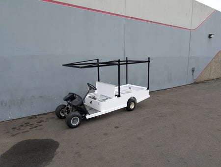 White custom flatbed golf cart with black metal frame installed, featuring FB-45X120-TLR FLATBED TOP LADDER RACK, 45″ X 120″ WITH REMOVABLE REAR CROSS BAR for hauling ladders and cargo.