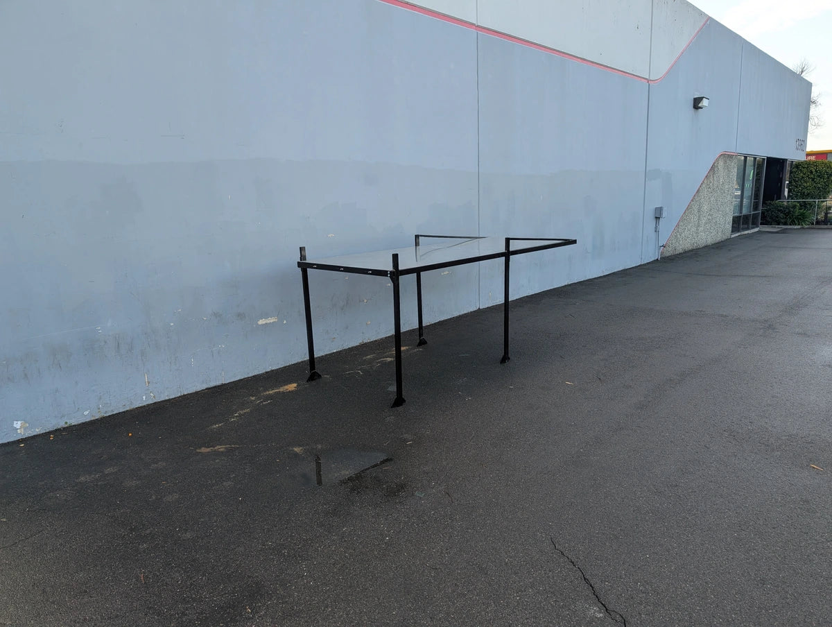 FB-45X120-TLR DECK 10 FT Top Mount Ladder Rack for Flatbed with Solid Deck shown standing outdoors on asphalt against a gray building wall, designed for custom fabrication for golf carts.