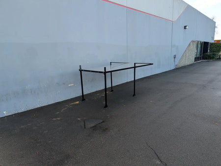 FB-45X120-TLR DECK 10 FT Top Mount Ladder Rack for Flatbed with Solid Deck shown standing outdoors on asphalt against a gray building wall, designed for custom fabrication for golf carts.